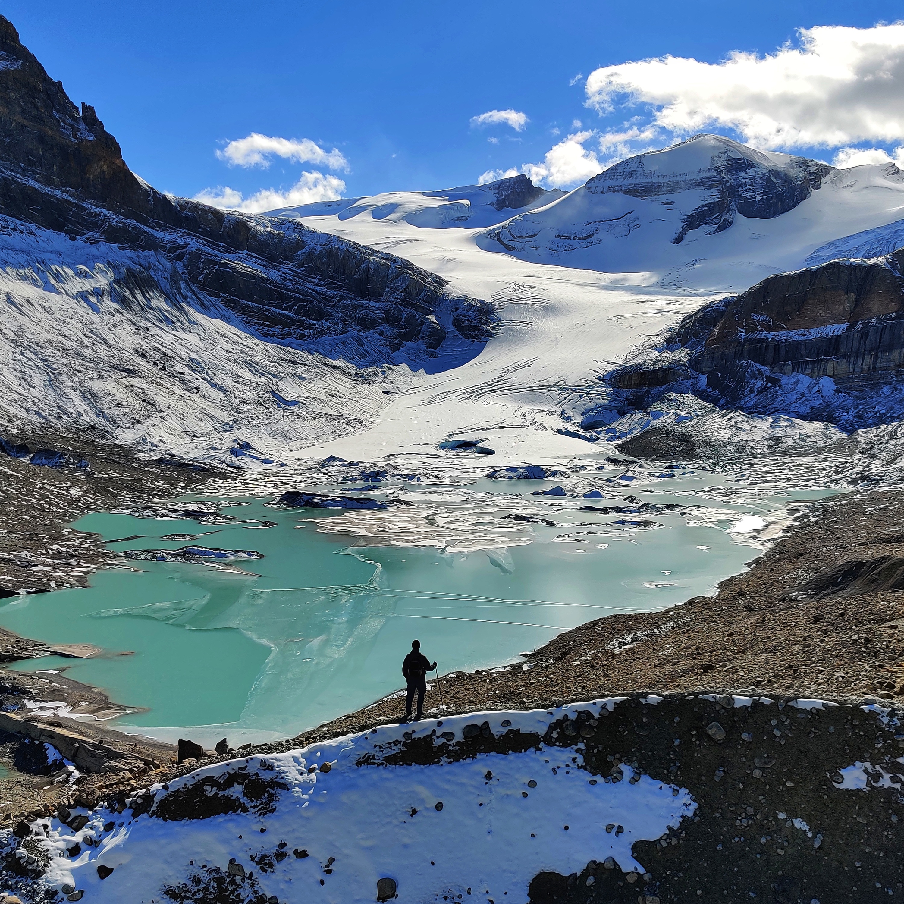 Will standing by a glacier-fed lake surrounded by snow-capped peaks.